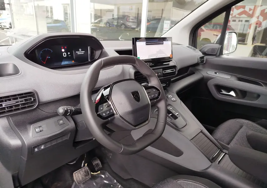 Vue intérieure côté conducteur du Peugeot Rifter 2026, tableau de bord moderne avec écran digital et volant compact noir.