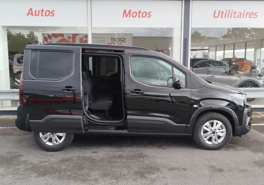 Vue de profil côté droit d’un Peugeot Rifter noir Perla Nera avec porte coulissante arrière ouverte, intérieur visible.