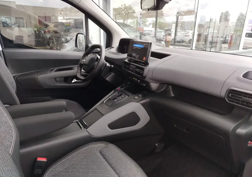 Vue intérieure côté conducteur du Peugeot Rifter 2026 noir Perla Nera, avec tableau de bord moderne et écran tactile central.