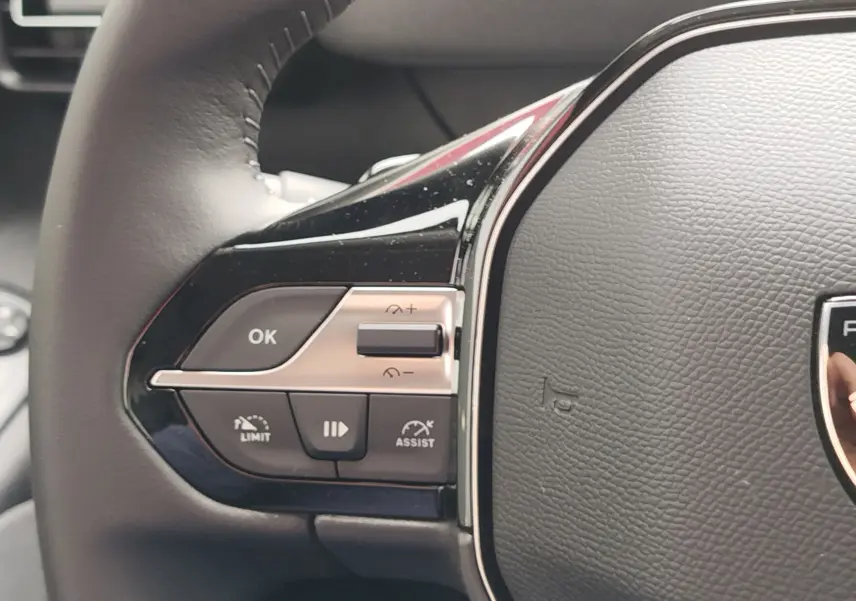 Gros plan sur les commandes à gauche du volant cuir du Peugeot Rifter noir, avec boutons de régulateur et assistant de conduite.