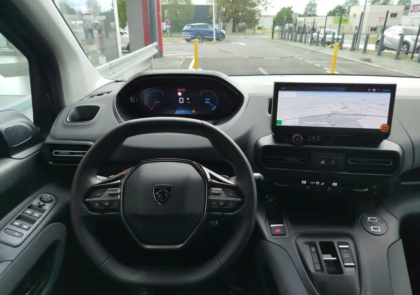 Vue intérieure du tableau de bord du Peugeot Rifter noir Perla Nera, avec volant multifonction et écran tactile central affichant la navigation.