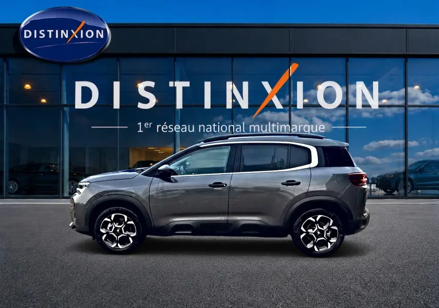 Profil côté gauche du Citroën C5 Aircross gris platinium 2025 avec jantes alu et barres de toit visibles.