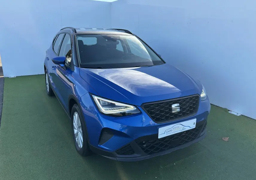 Vue 3/4 avant d'un SEAT Arona bleu saphir avec toit noir, calandre noire et jantes alliage 16 pouces.