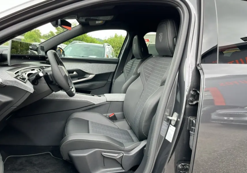 Vue intérieure côté conducteur du Peugeot 5008 Hybrid 145 GT 2025, sièges cuir gris avec logo Peugeot brodé.
