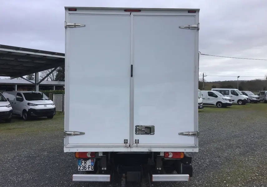 Vue arrière d’un utilitaire blanc Opel Movano Chassis Cabine L3H1 avec hayon électrique, stationné sur un terrain extérieur.