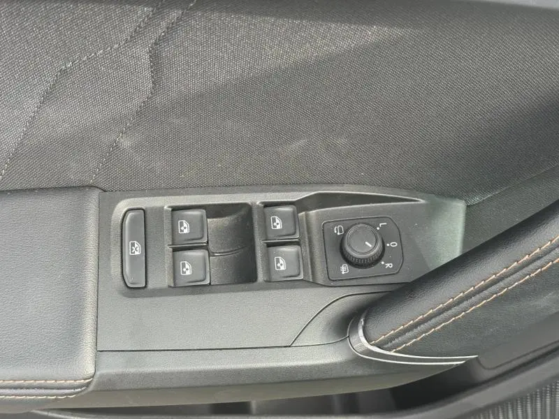 Détail des commandes de lève-vitres et réglage des rétroviseurs côté gauche intérieur d'une CUPRA Formentor bleu.