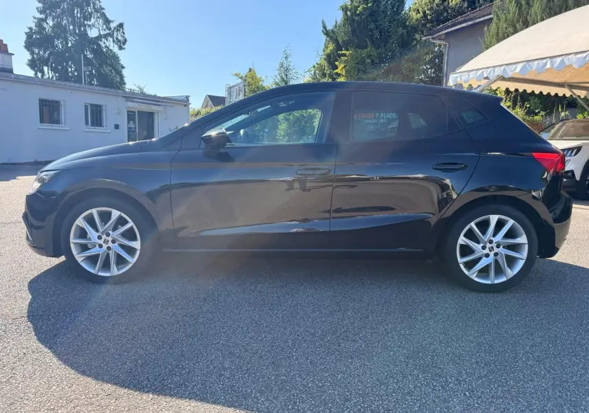 Profil latéral droit d'une SEAT Ibiza noire 2025 avec jantes alliage et vitres teintées, stationnée en extérieur.
