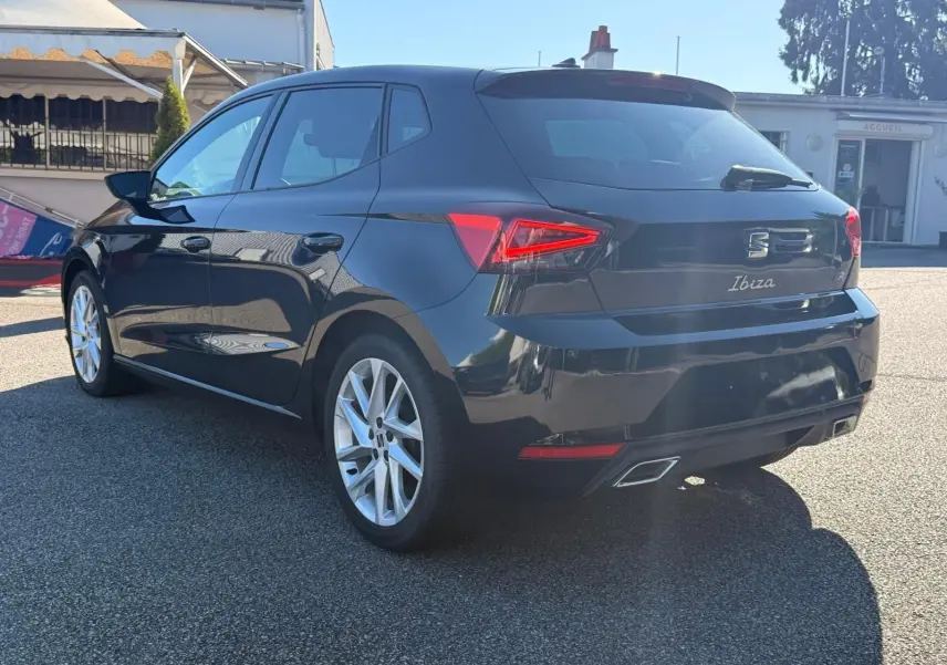 Vue 3/4 arrière droite d'une SEAT Ibiza noire 2025 avec feux LED et double sortie d'échappement chromée.