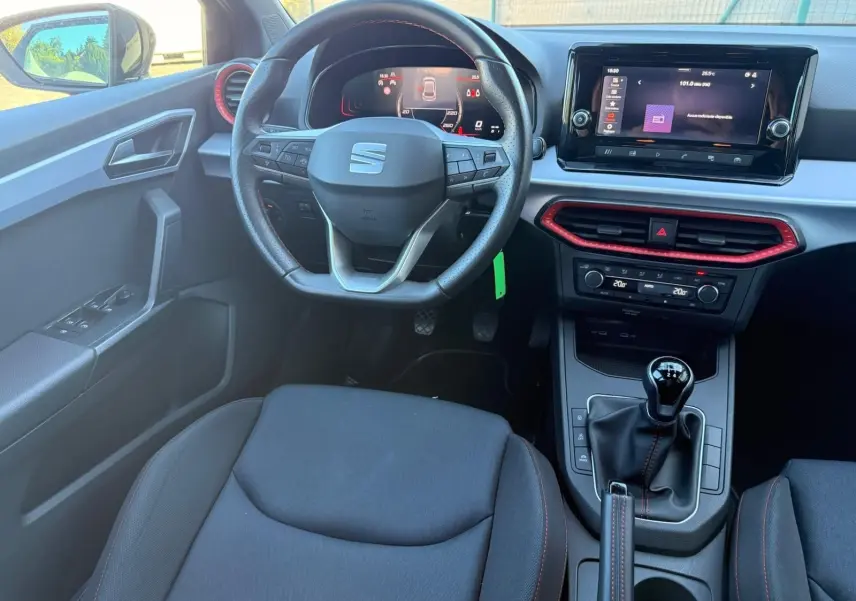 Vue intérieure avant du poste de conduite de la SEAT Ibiza noire, volant cuir multifonctions et écran tactile central.