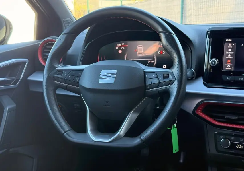 Vue intérieure centrée sur le volant cuir noir perforé de la SEAT Ibiza 2025 avec tableau de bord digital et écran tactile.