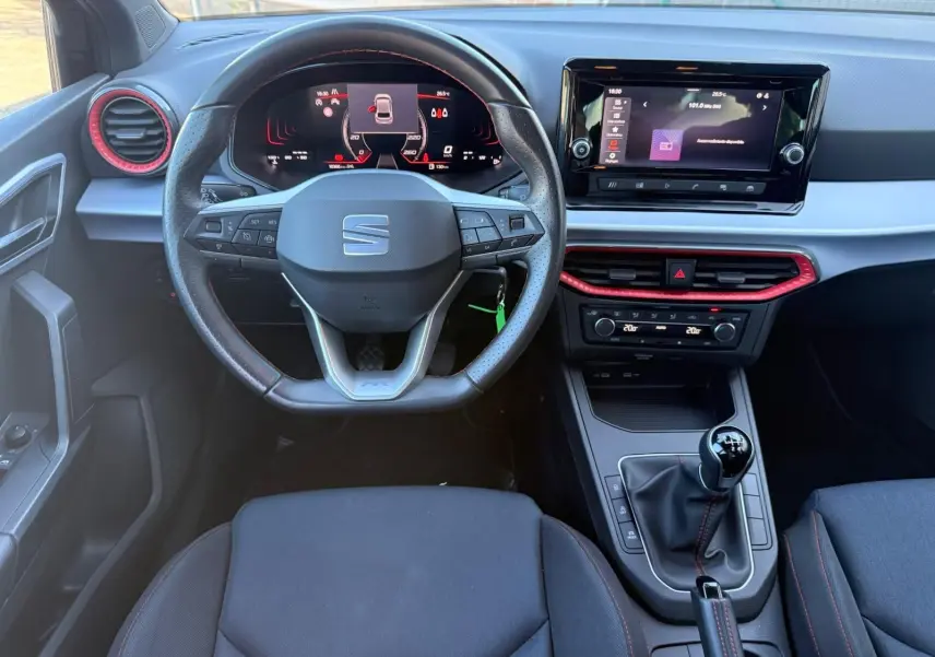 Vue intérieure frontale du tableau de bord et volant noir de la SEAT Ibiza 1.0 TSI 95 FR avec détails rouges et écran tactile.
