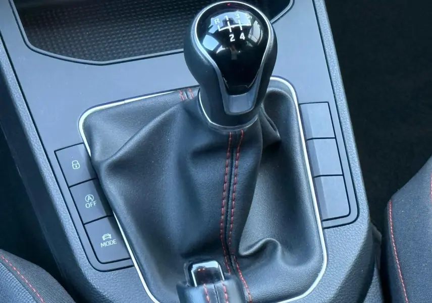 Gros plan sur le levier de vitesses manuel noir avec surpiqûres rouges de la SEAT Ibiza 1.0 TSI 95 FR 2025.