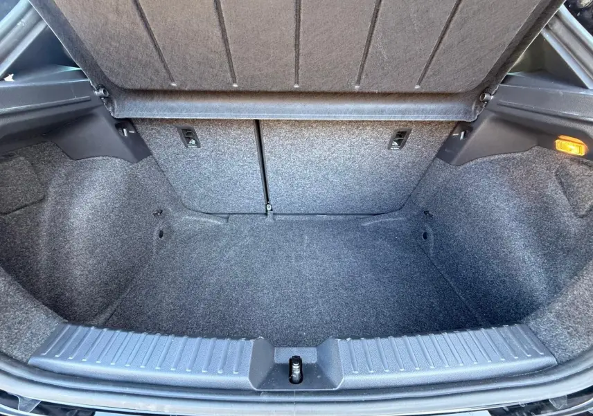Coffre ouvert de la SEAT Ibiza 1.0 TSI 95 FR noir, vue intérieure montrant l'espace de rangement et la moquette grise.