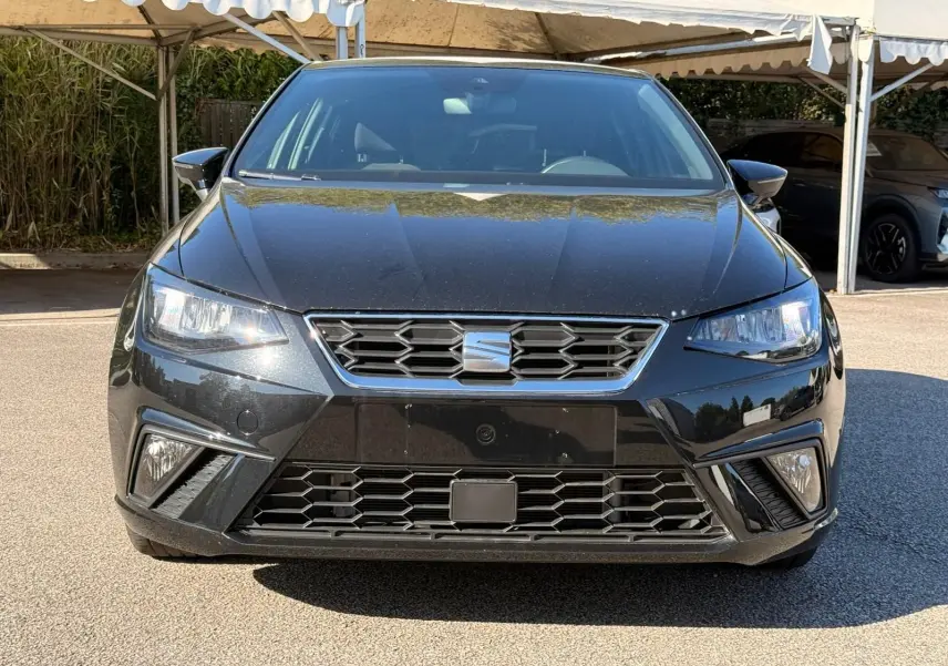 Vue avant d'une SEAT Ibiza 1.0 TSI 95 FR noire, avec calandre hexagonale et feux LED allumés.