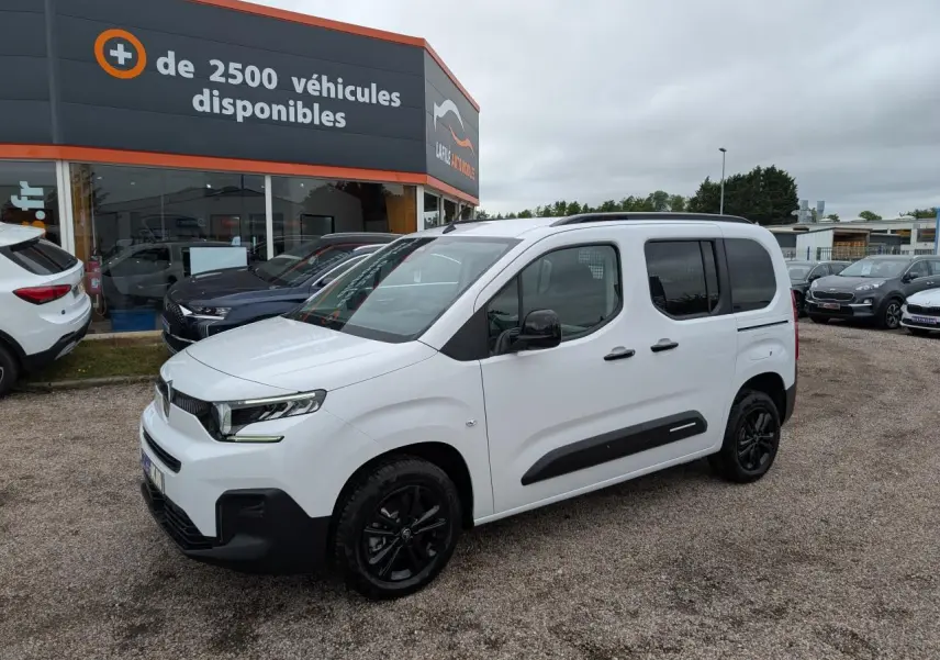 Citroën Berlingo blanc en 3/4 avant droit avec barres de toit noires et jantes alliage noires.