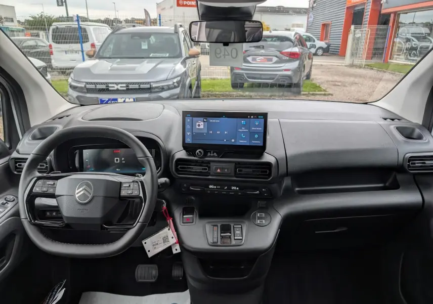 Vue intérieure avant du tableau de bord du Citroën Berlingo blanc 2025 avec écran tactile et volant multifonctions cuir.