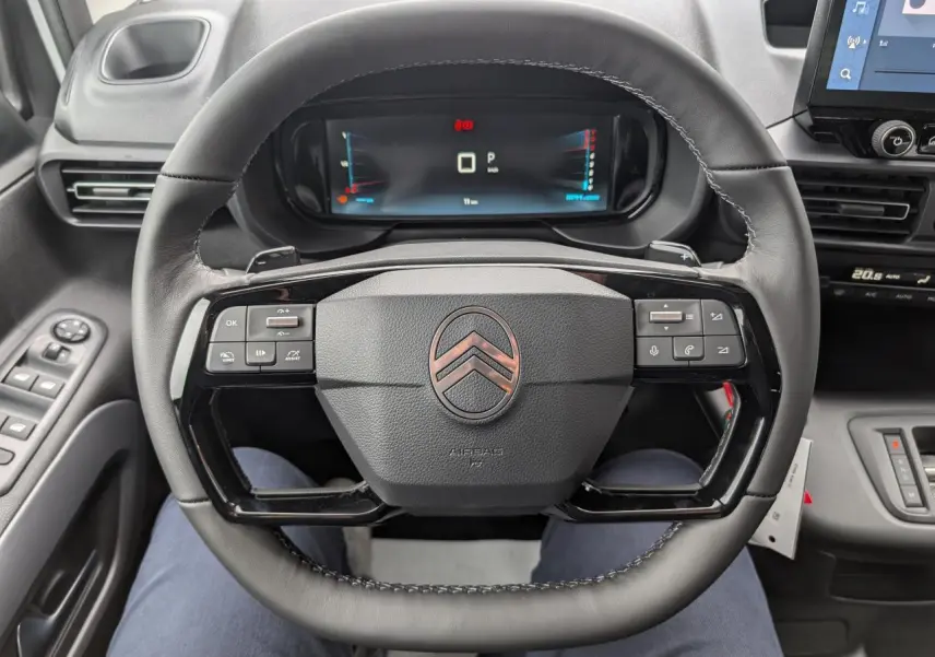 Vue intérieure centrée sur le volant cuir multifonctions noir du Citroën Berlingo 2025 avec tableau de bord numérique.
