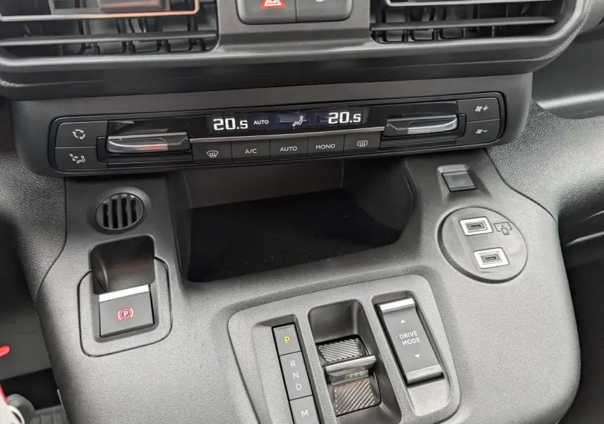 Vue rapprochée de la console centrale noire du Citroën Berlingo 2025 avec commandes climatisation et boîte auto.