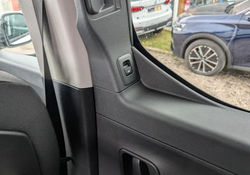 Détail intérieur côté gauche montrant la poignée et la commande de la porte coulissante du Citroën Berlingo blanc.