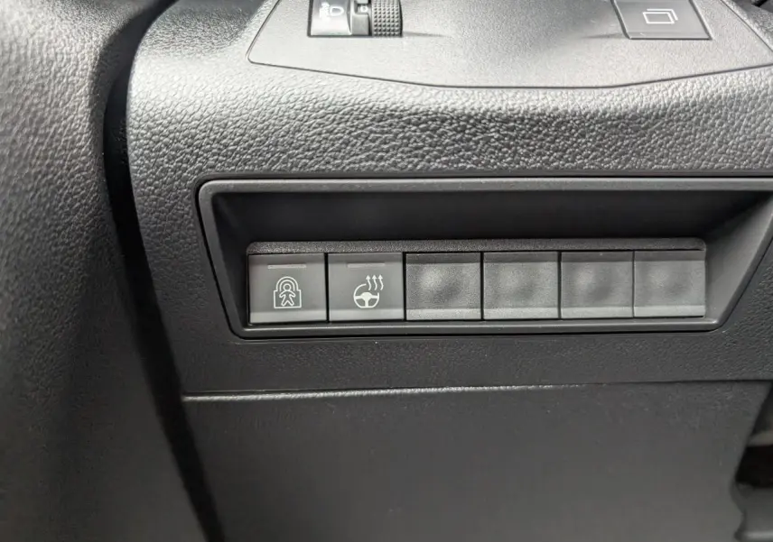 Gros plan sur les boutons de commande noirs du tableau de bord côté conducteur du Citroën Berlingo blanc 2025.
