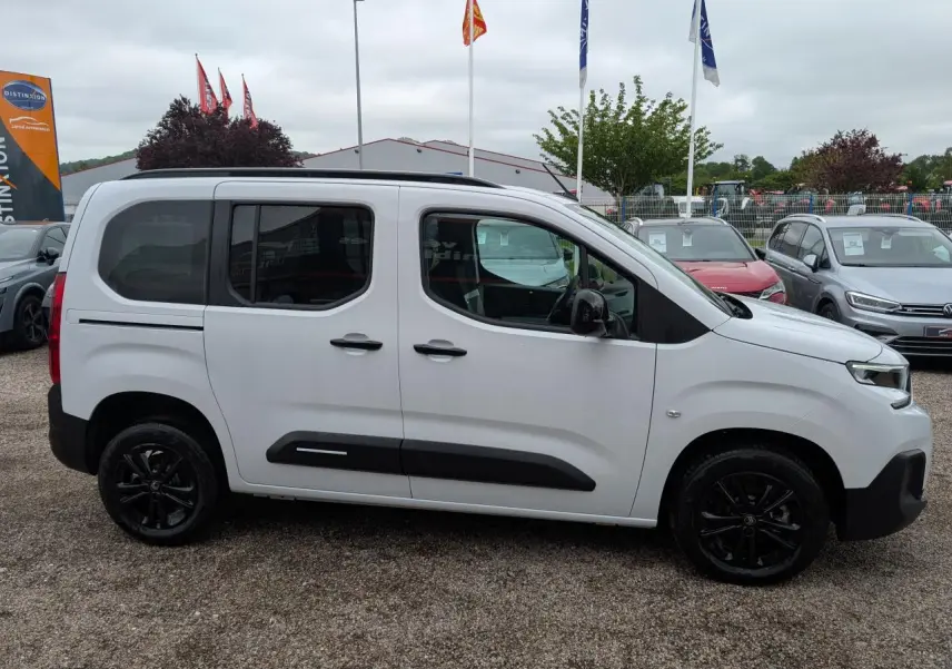 Vue de profil côté gauche d'un Citroën Berlingo blanc avec barres de toit noires et jantes alliage noires.