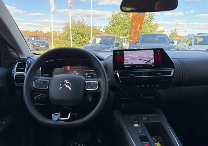 Vue intérieure du poste de conduite du Citroën C5 Aircross blanc 2025, avec écran tactile et volant multifonction.