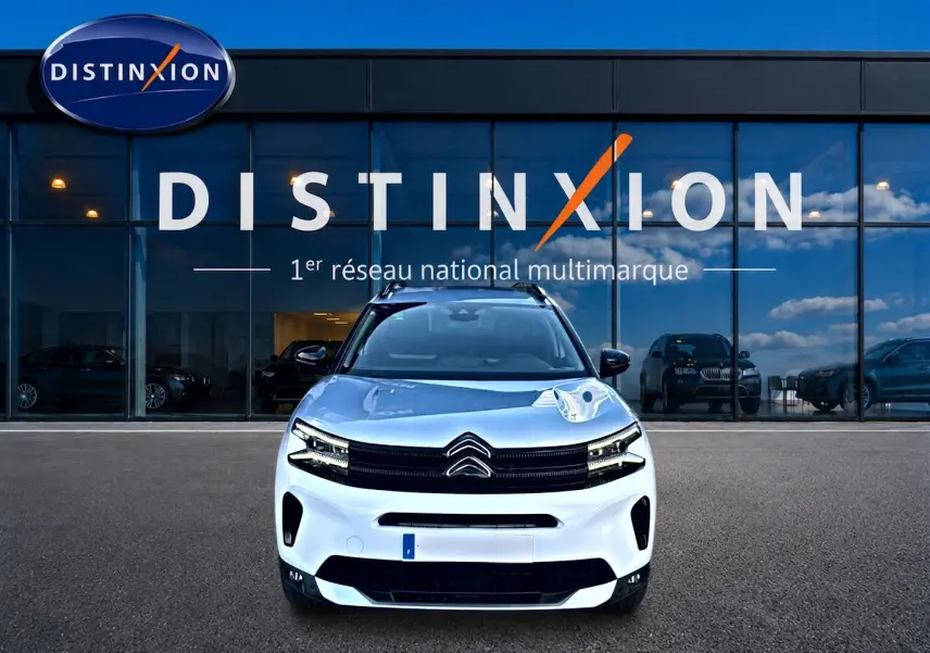 Citroën C5 Aircross blanc vue de face avec calandre noire et barres de toit devant showroom Distinxion.