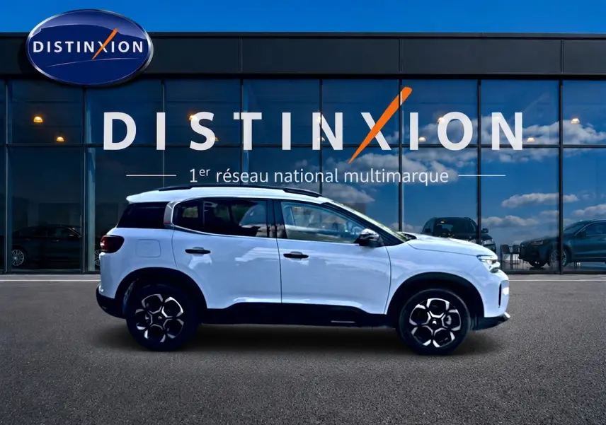 Vue latérale droite d'un Citroën C5 Aircross blanc 2025 avec jantes alu et barres de toit noires.
