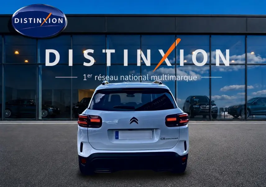 Vue arrière d'un Citroën C5 Aircross blanc 2025, avec feux LED et barres de toit visibles devant une vitrine Distinxion.