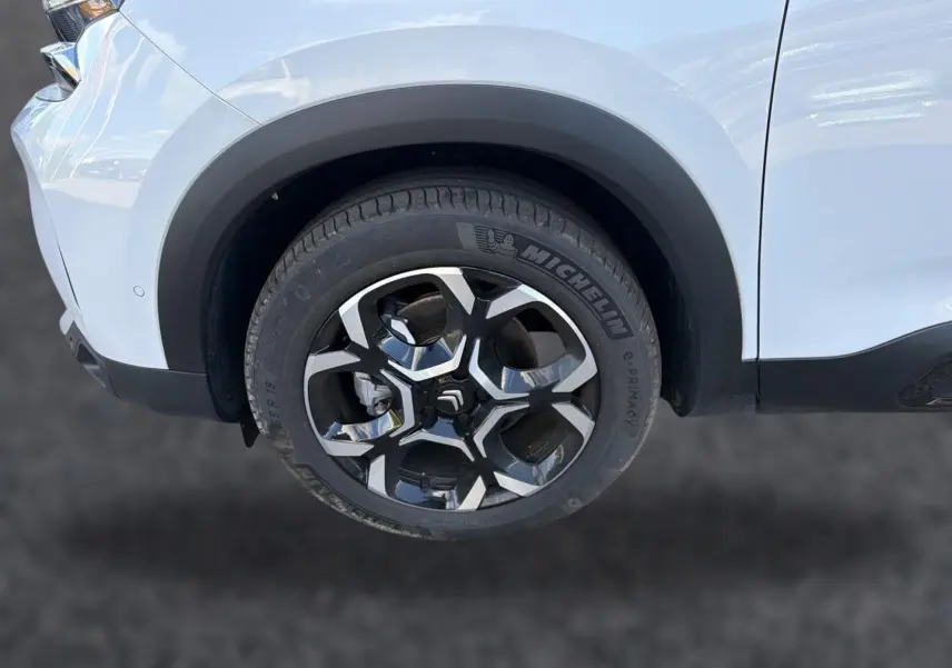 Gros plan sur la roue avant droite du Citroën C5 Aircross blanc avec jante alliage noire et argentée.