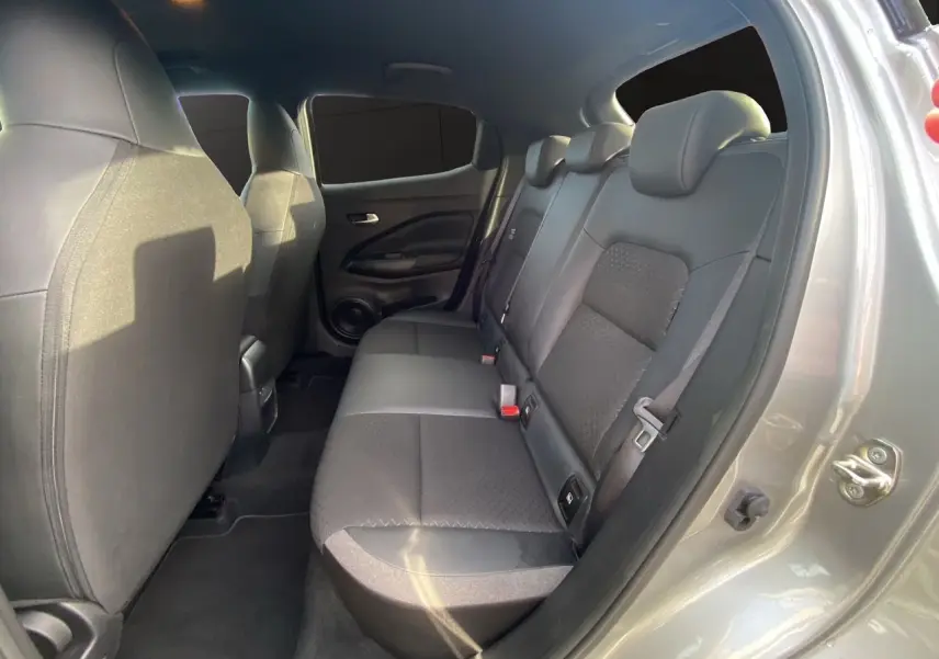 Vue intérieure côté droit sur la banquette arrière noire en tissu du Nissan Juke 2025 gris perle avec toit noir.