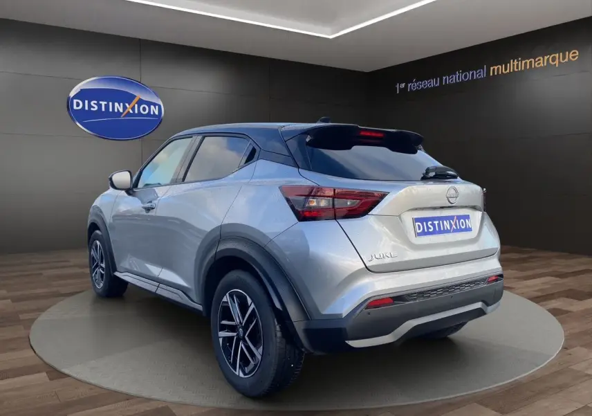 Nissan Juke 2025 gris perle avec toit noir, vue 3/4 arrière droit, jantes alliage 17 pouces et feux LED.