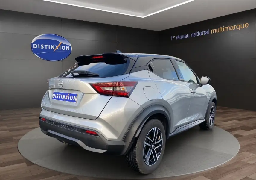 Vue 3/4 arrière droite du Nissan Juke gris perle avec toit noir et jantes alliage 17 pouces en showroom.