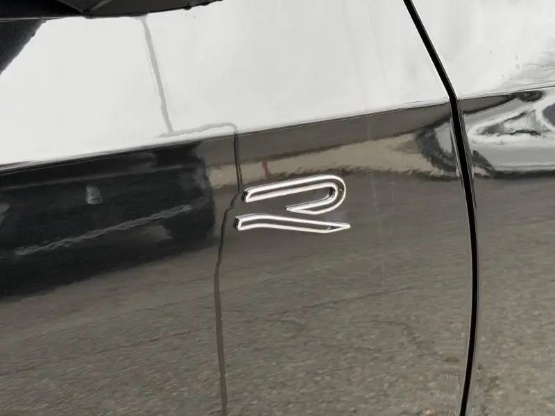 Détail de l’emblème R sur la porte noire d’une Volkswagen Golf 2.0 TDI 150ch R-Line 2026 vue de côté gauche.