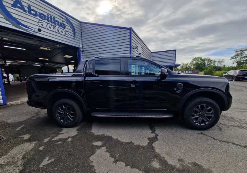 Vue de profil côté gauche du Ford Ranger Double Cabine noir 2023, avec marchepied et rideau de plateau coulissant visible.