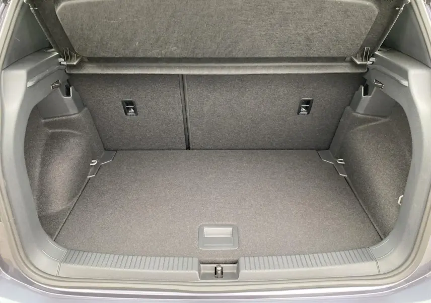 Coffre ouvert gris du Volkswagen T-Cross 2024, vue intérieure montrant l'espace de rangement et la moquette.