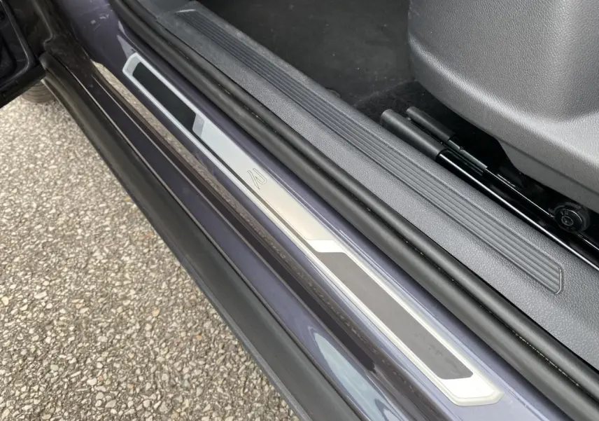 Gros plan sur le seuil de porte côté conducteur gris métallisé du Volkswagen T-Cross 2024 avec logo R-Line.