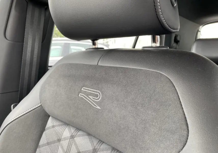 Gros plan sur l’appuie-tête et dossier de siège avant gris foncé avec logo R brodé, intérieur Volkswagen T-Cross.