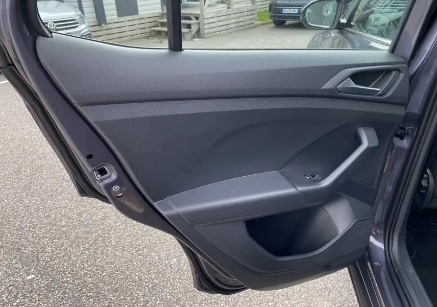 Vue intérieure de la porte arrière droite grise du Volkswagen T-Cross 2024 avec poignée et commande de vitre.