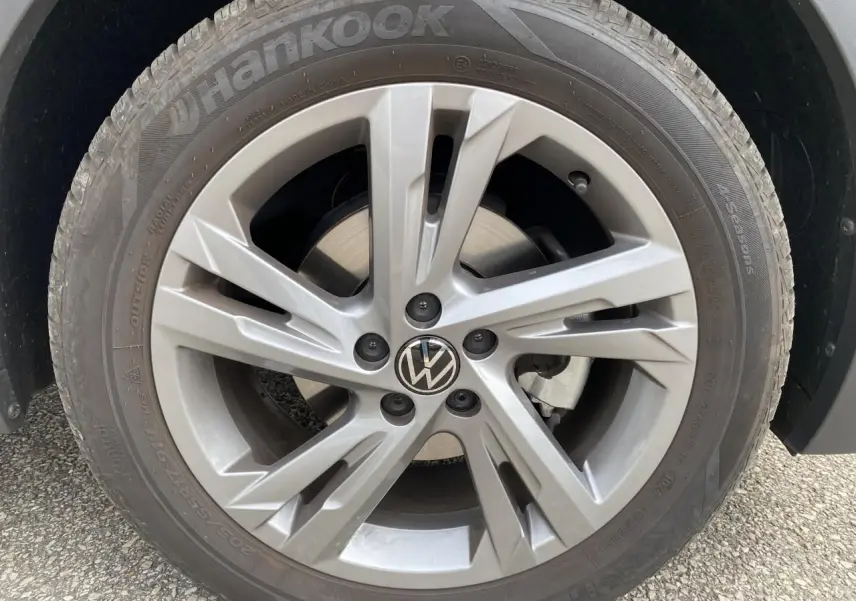 Gros plan sur la roue avant droite avec jante alliage grise et logo Volkswagen au centre.