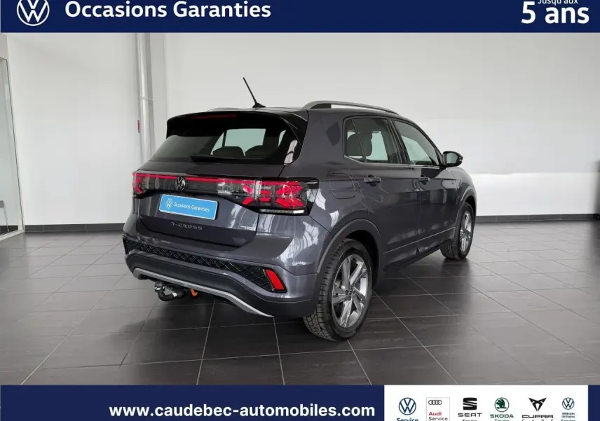 Volkswagen T-Cross gris en 3/4 arrière droit, avec attelage amovible, dans un showroom lumineux.