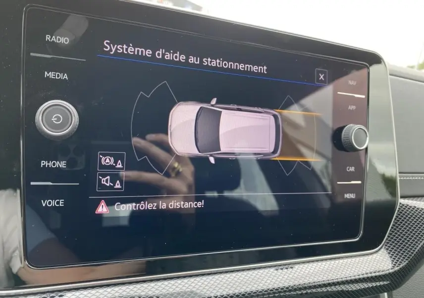 Écran tactile du système d'aide au stationnement montrant un Volkswagen T-Cross gris vu de dessus.