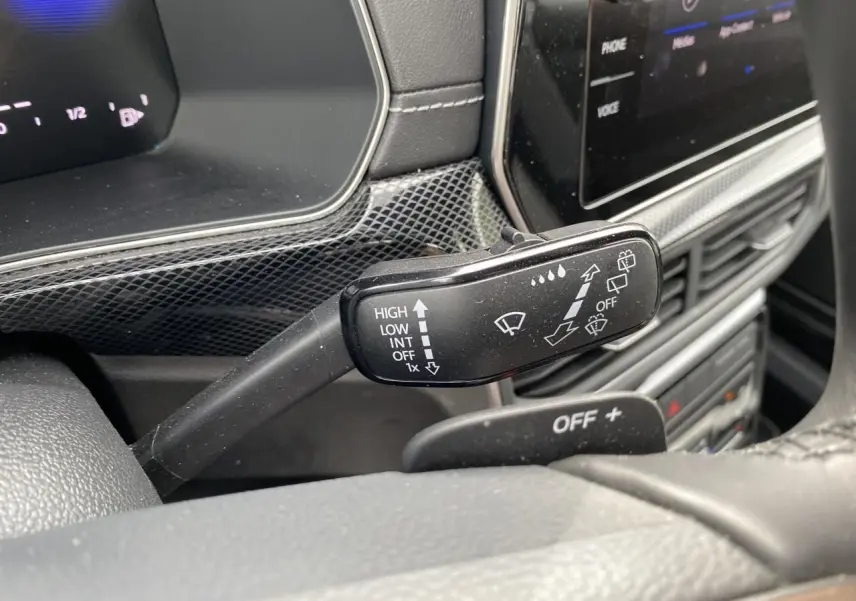 Gros plan sur la commande d’essuie-glace du Volkswagen T-Cross gris 2024, avec tableau de bord et écran tactile en arrière-plan.