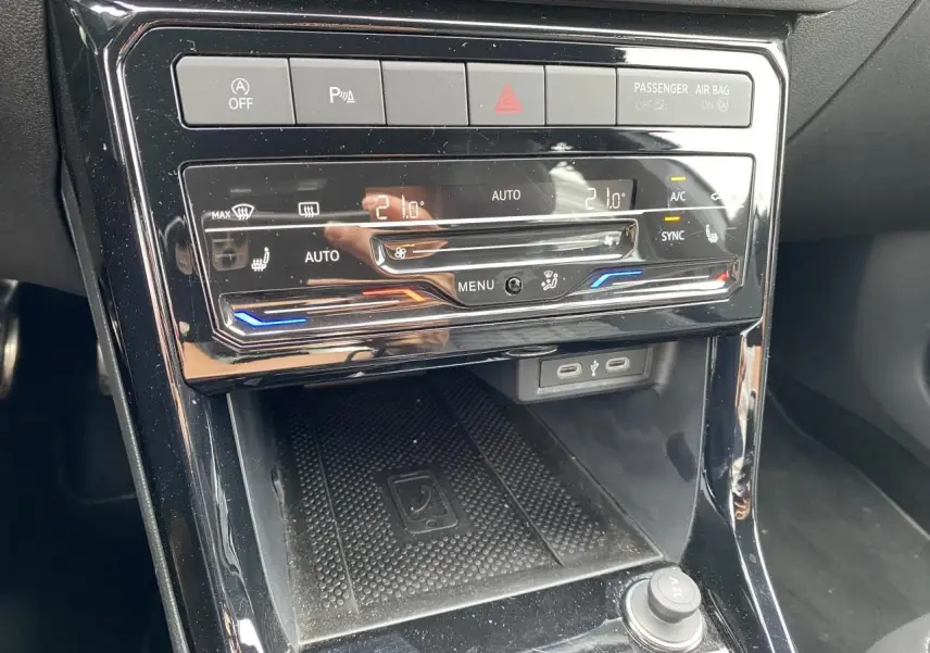 Vue rapprochée de la console centrale noire du Volkswagen T-Cross avec commandes climatisation tactile et ports USB-C.