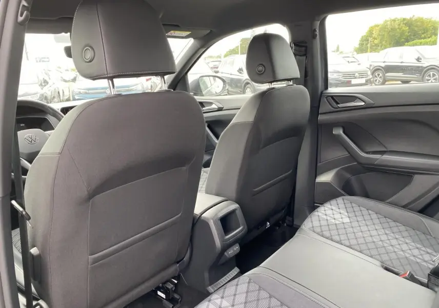 Vue intérieure arrière du Volkswagen T-Cross gris, montrant les sièges avant et la banquette arrière en tissu.