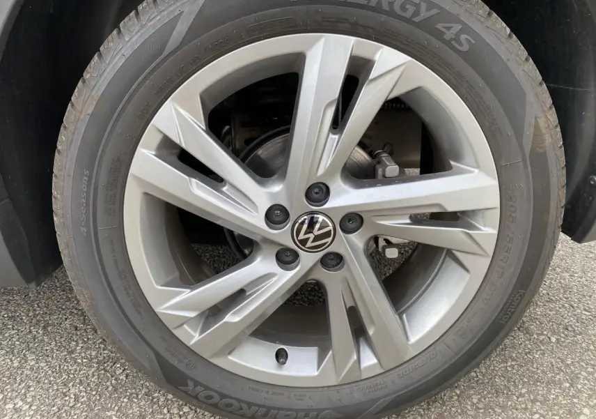 Gros plan sur la jante alliage grise avec logo Volkswagen du Volkswagen T-Cross 2024, pneu Hankook 4 saisons.