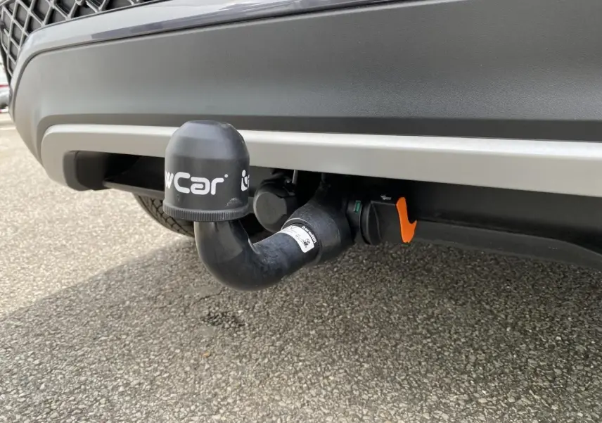 Gros plan sur l'attelage amovible noir sous le pare-chocs arrière gris du Volkswagen T-Cross 2024.