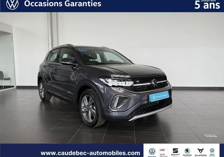 Volkswagen T-Cross gris en 3/4 avant droit, avec calandre noire et jantes alliage visibles en showroom.