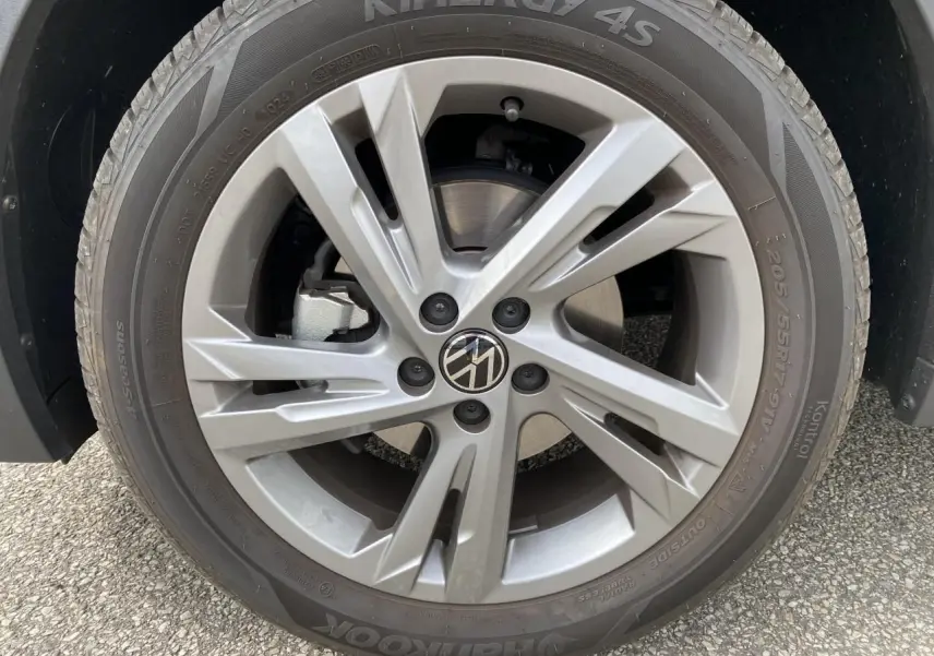 Gros plan sur la roue avant droite du Volkswagen T-Cross gris avec jante alliage et logo VW au centre.