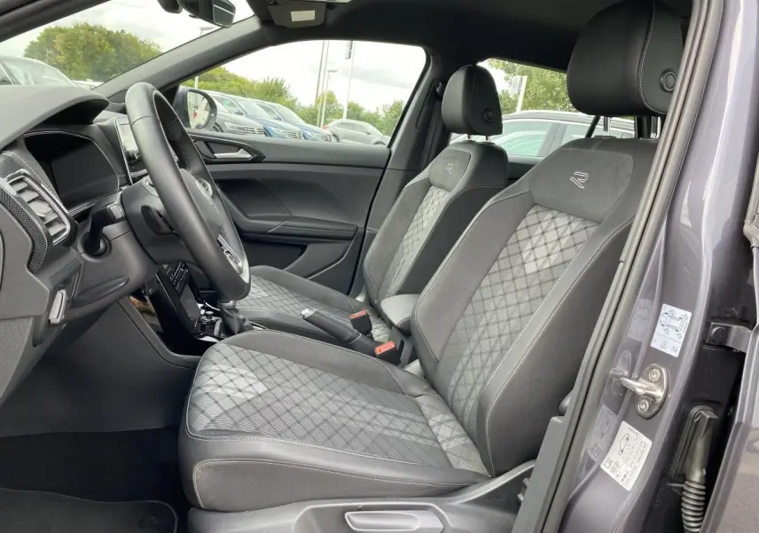 Vue intérieure côté conducteur du Volkswagen T-Cross gris 2024, sièges avant avec surpiqûres et logo R brodé.